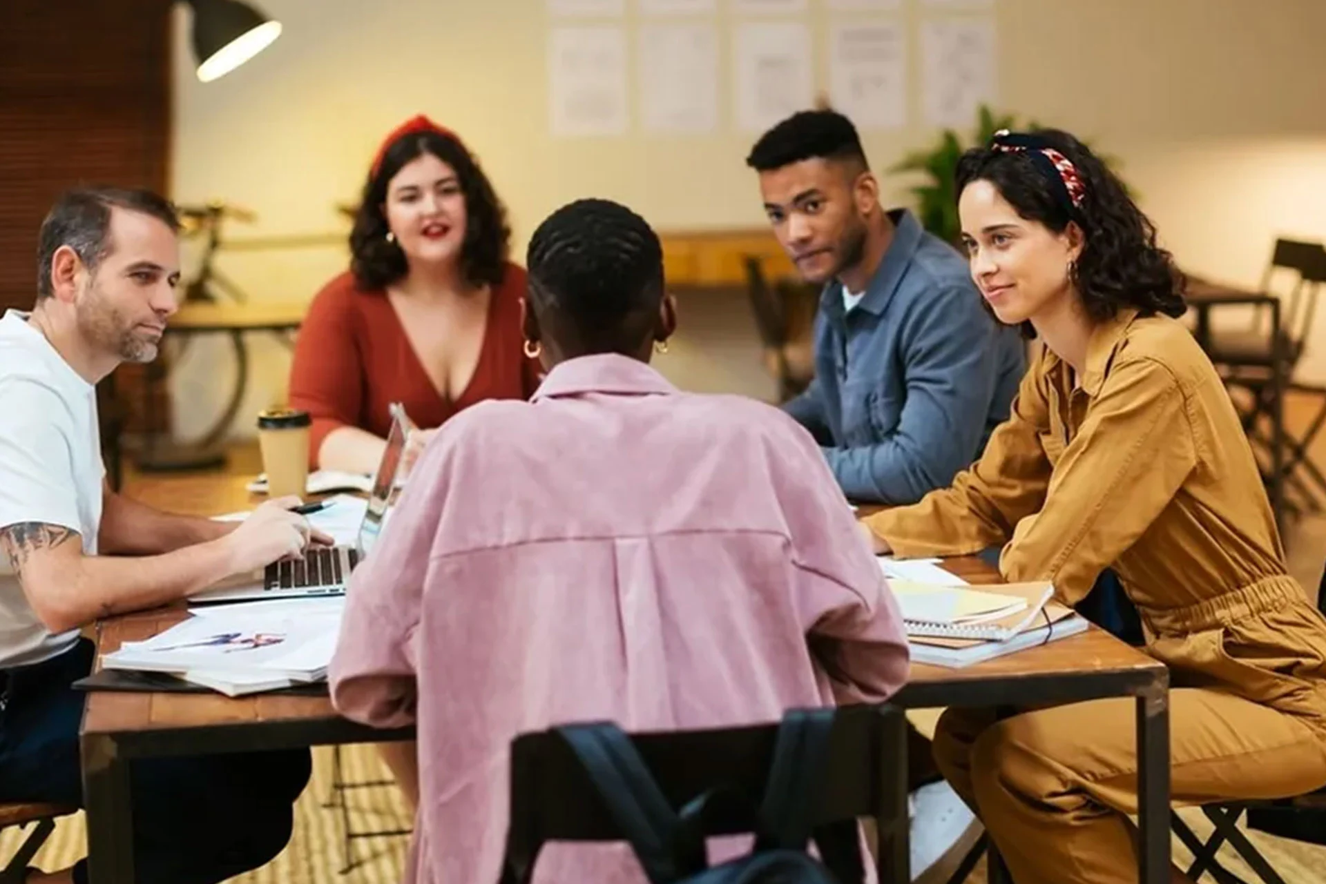 A diverse group of people collaborating around a table, discussing future work standards and strategies