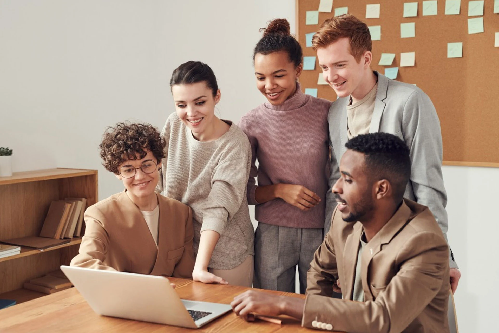 A group of diverse people collaborating around a laptop, embodying the theme of transforming the way you work