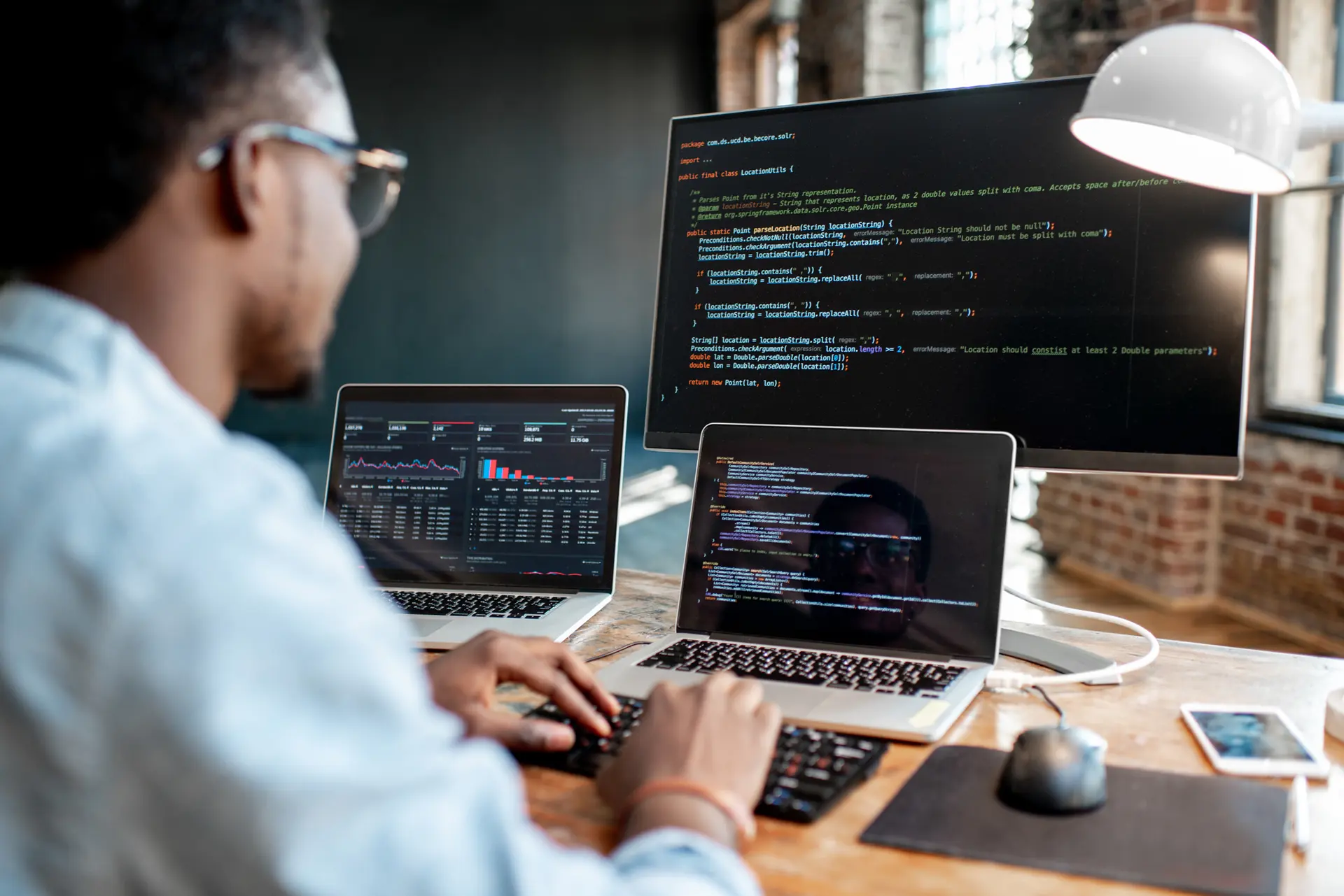 Man focused on his laptop and computer, engaged in custom software development work