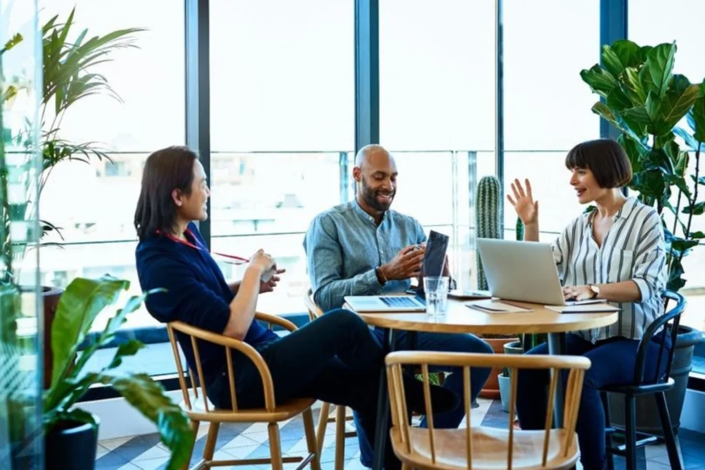 Group of people collaborating at a table with laptops, focused on developing a Proprietary Customer Acquisition System (CAS)