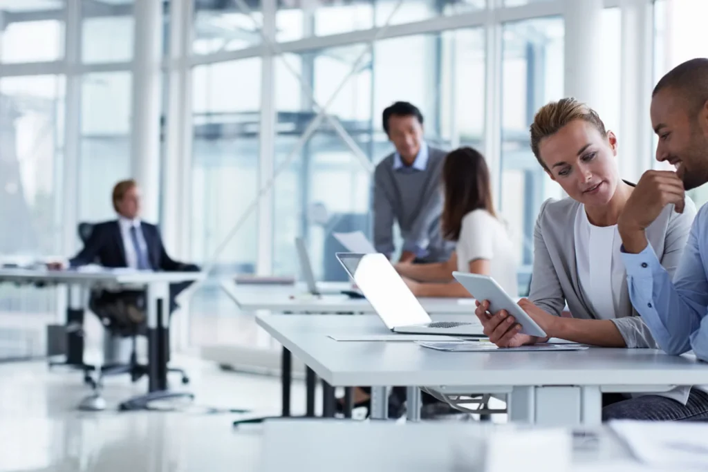 Man and woman collaborate at a table with a laptop, focusing on investing for sustainable passive income