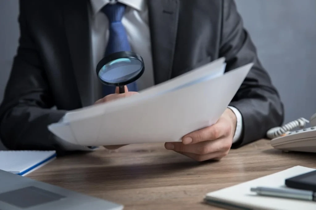 Man in a suit examines a paper with a magnifying glass, illustrating the concept of passive income in practice